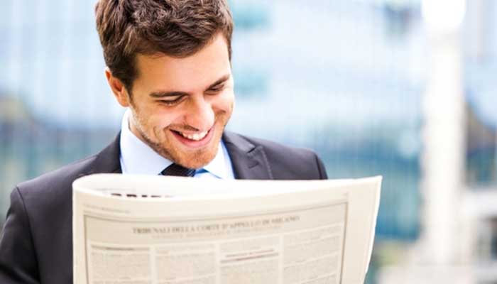 man reading newspaper article grey and grey marketing facilitation brisbane