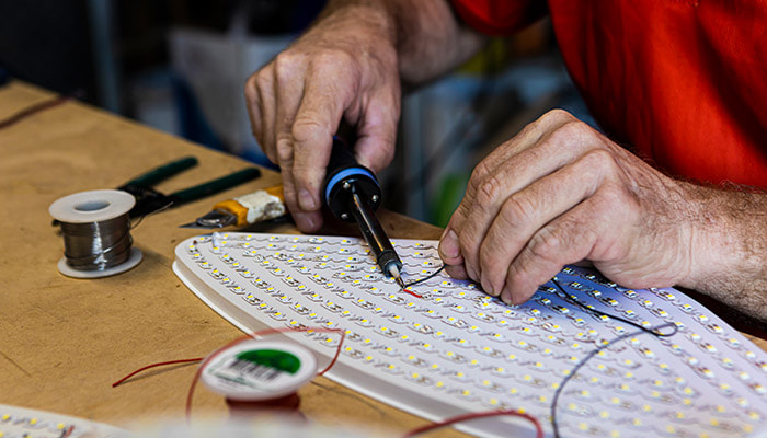 Signwriter soldering LEDs into signage in Brisbane